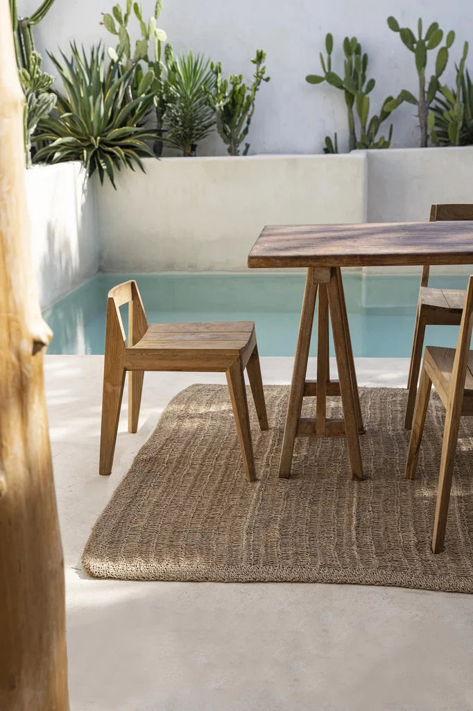 Vue d’une salle à manger extérieure avec un ensemble en bois sur rugue tissée naturelle