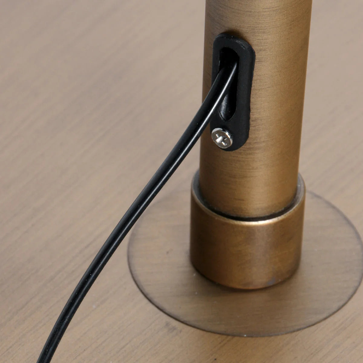 Câble noir connecté à un lampadaire en métal doré avec abat-jour en rotin ajouré