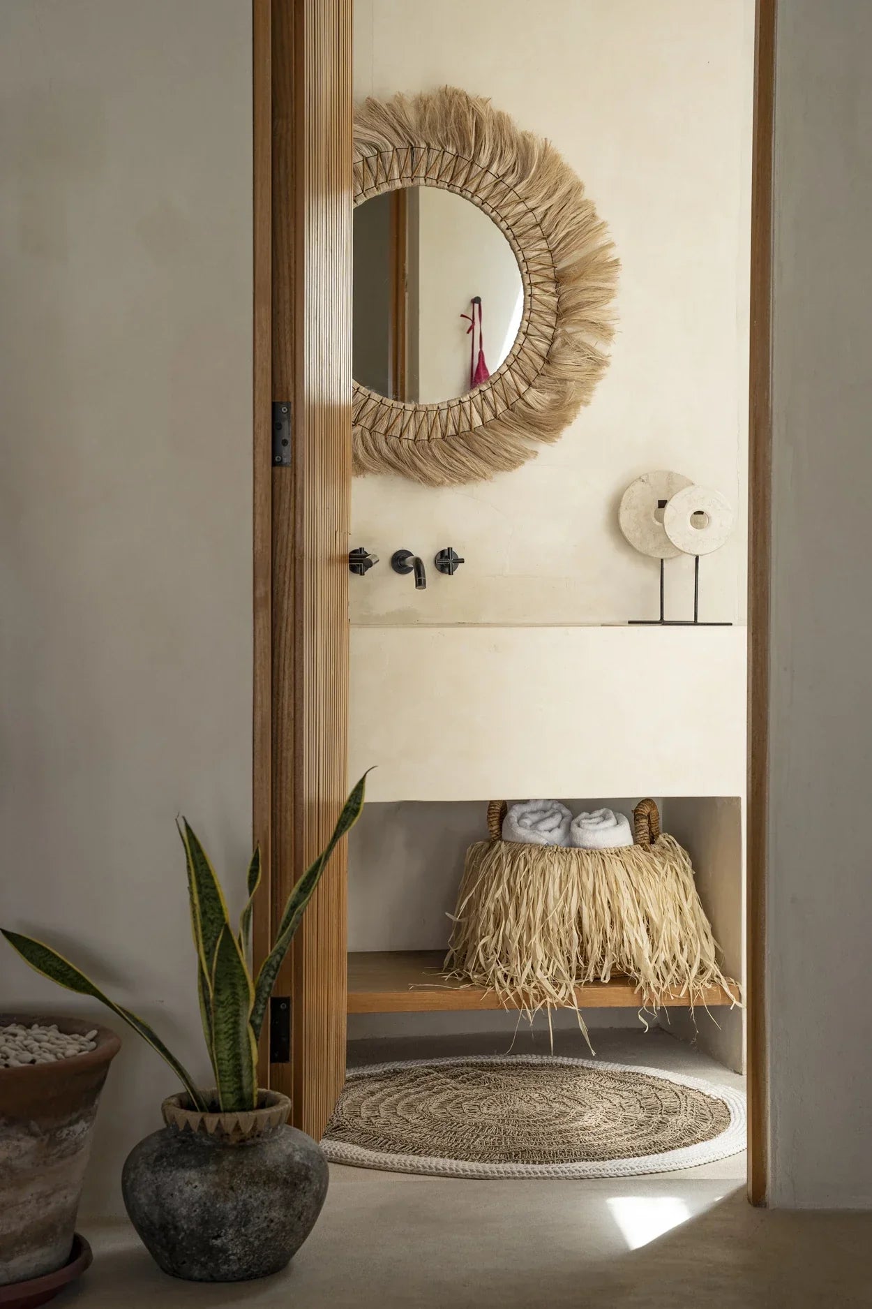 Panier de rangement rond en feuilles de bananier avec franges en raphia naturel dans salle de bain bohème