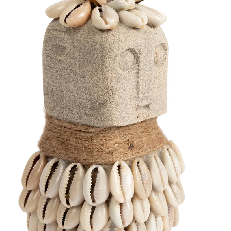 Figure en pierre ornée de coquillages et de ficelle.