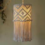 Abat-jour boho en coton tressé allumé, créant une lumière chaleureuse et tamisée.