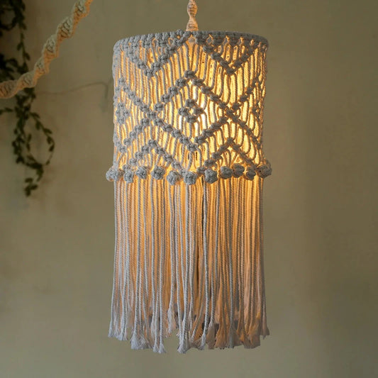 Abat-jour boho en coton tressé allumé, créant une lumière chaleureuse et tamisée.