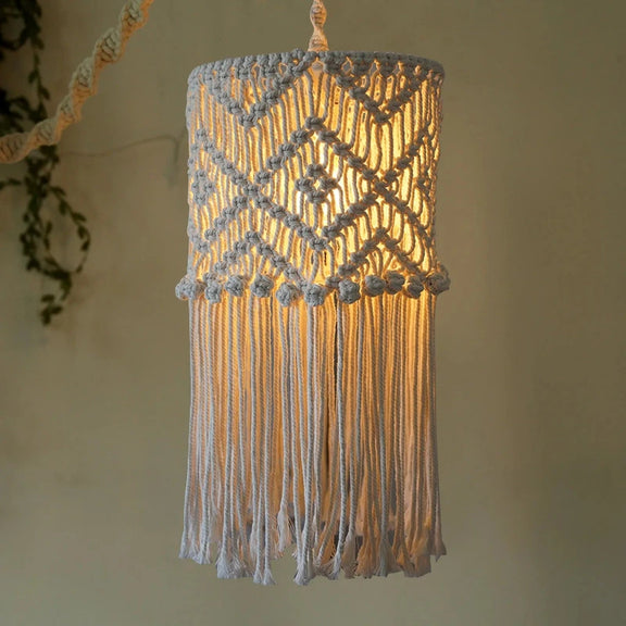 Abat-jour boho en coton tressé allumé, créant une lumière chaleureuse et tamisée.