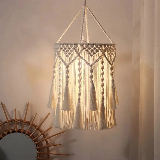 Abat-jour en macramé à franges suspendu éclairé dans une ambiance chaleureuse.