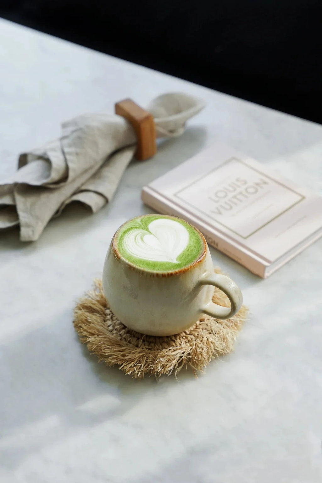 Tasse en céramique crème avec matcha latte au cœur blanc et anneaux de serviette en teck