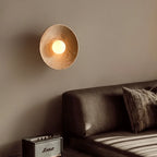 Gros plan sur l'applique murale en bois avec une ampoule blanc chaud allumée, montrant la diffusion de la lumière.