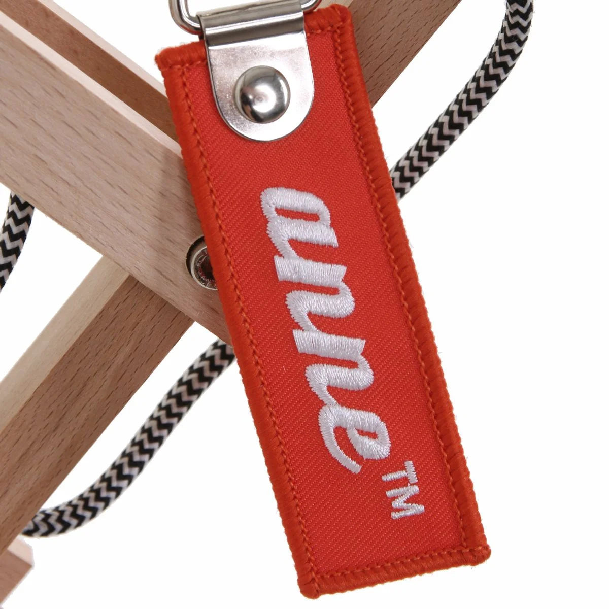 Étiquette en tissu rouge avec lettrage blanc sur lampadaire mural en bois naturel et abat-jour blanc conique