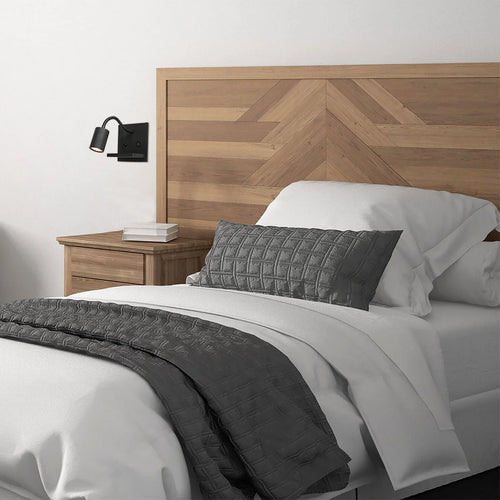Applique murale noire en métal avec chargeur sans fil et ports USB dans une chambre avec tête de lit en bois