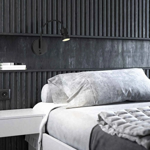 Applique murale noire en métal avec port USB dans une chambre moderne avec literie grise
