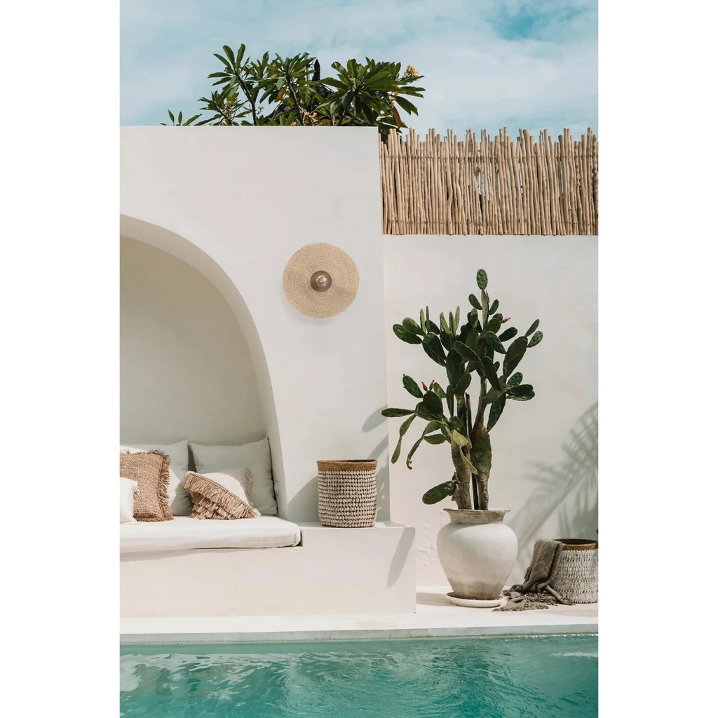 Espace extérieur moderne avec banc, applique murale ronde en rotin et cactus près de la piscine