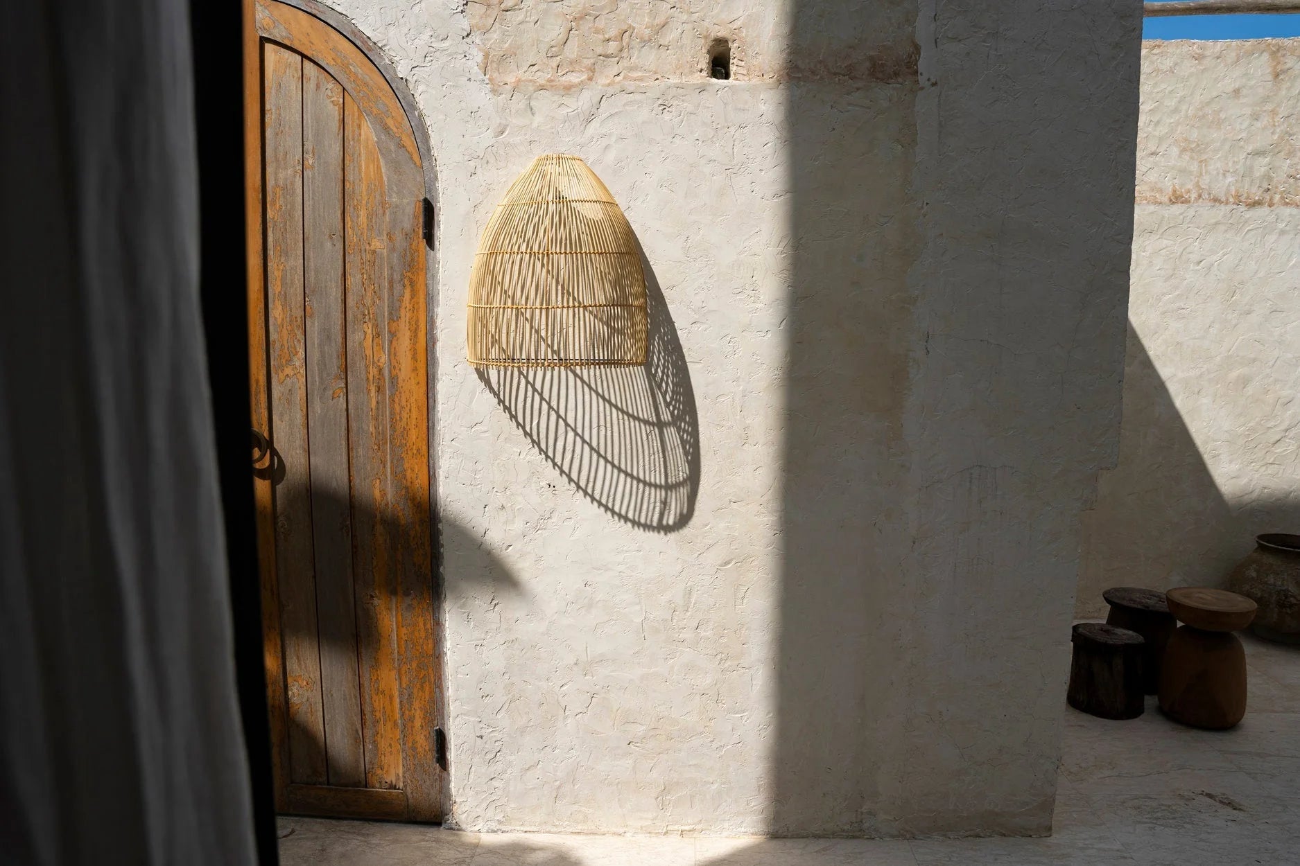 Applique murale en rotin naturel conique ajourée H55 cm sur mur stuc blanc