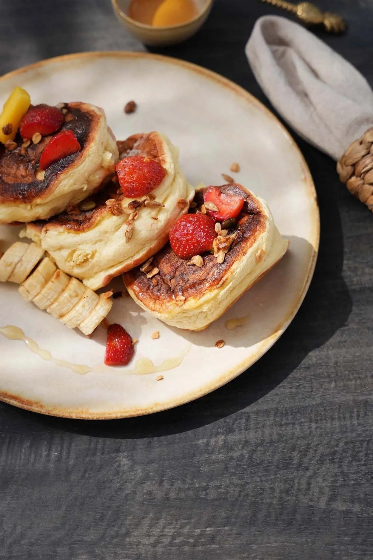 Assiette en grès blanc cassé bord doré avec pancakes, fraises, bananes et granola