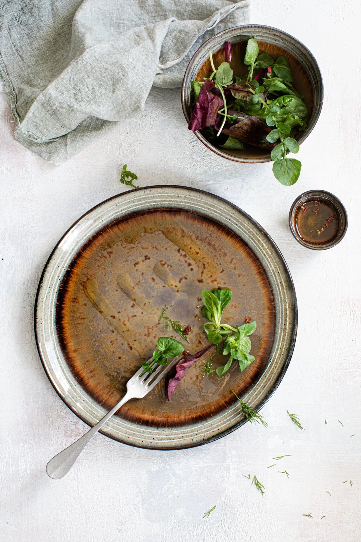 Assiette en grès émaillé brun avec bord texturé et restes de salade