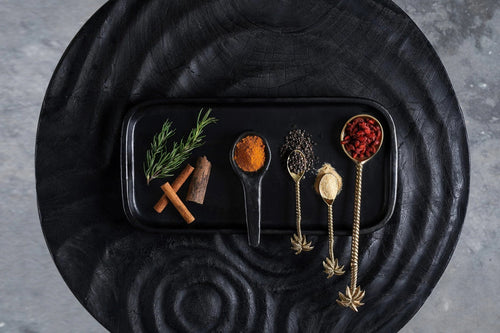 Assiette rectangulaire noire mate avec épices et herbes dans cuillères dorées ornées