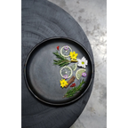 Assiette ronde en terracotta brûlée noir mat Ø30 cm garnie de citron, romarin et fleurs