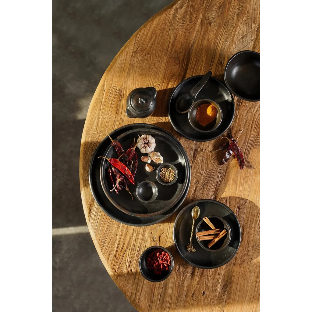 Assiette ronde en terracotta brûlée noire mat avec bols et épices assorties