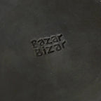 Assiette ronde en terracotta brûlée noir mat avec cuir noir embossed Bazar Bizar logo