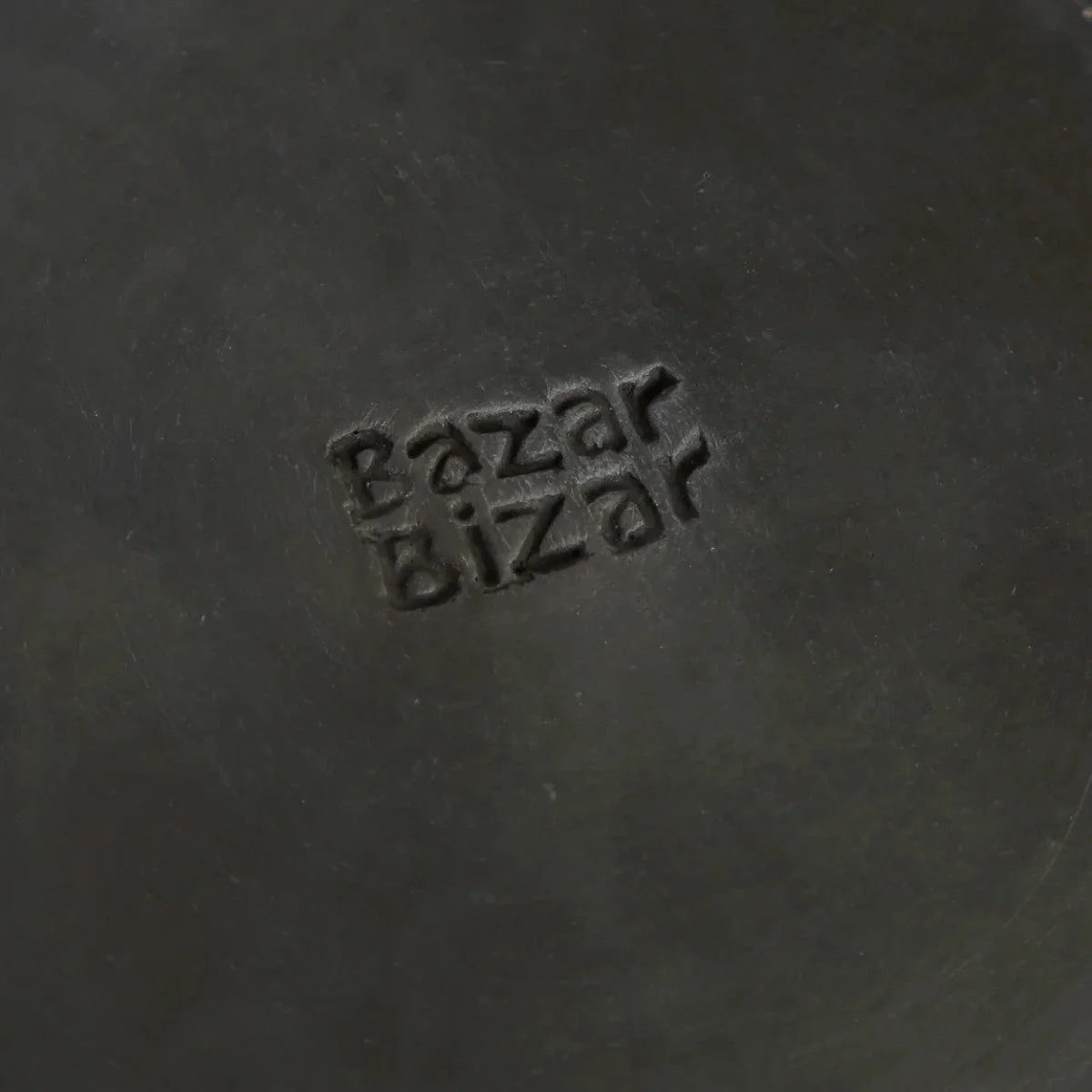 Assiette ronde en terracotta brûlée noir mat avec cuir noir embossed Bazar Bizar logo