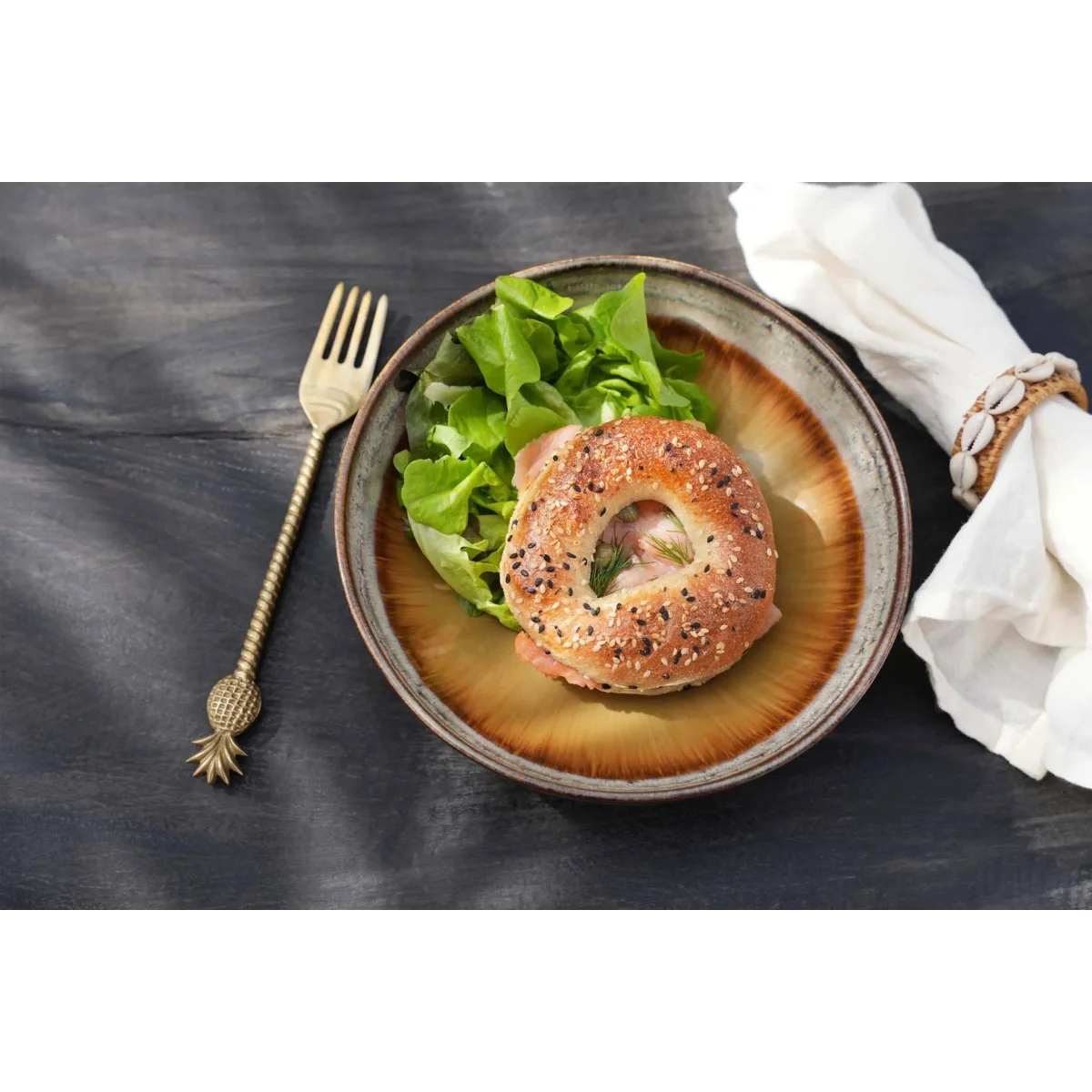 Bagel aux graines de sésame et pavot, garni de légumes verts et de pâte rose