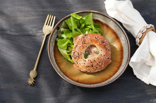 Bagel aux graines de sésame et pavot, garni de légumes verts et de pâte rose