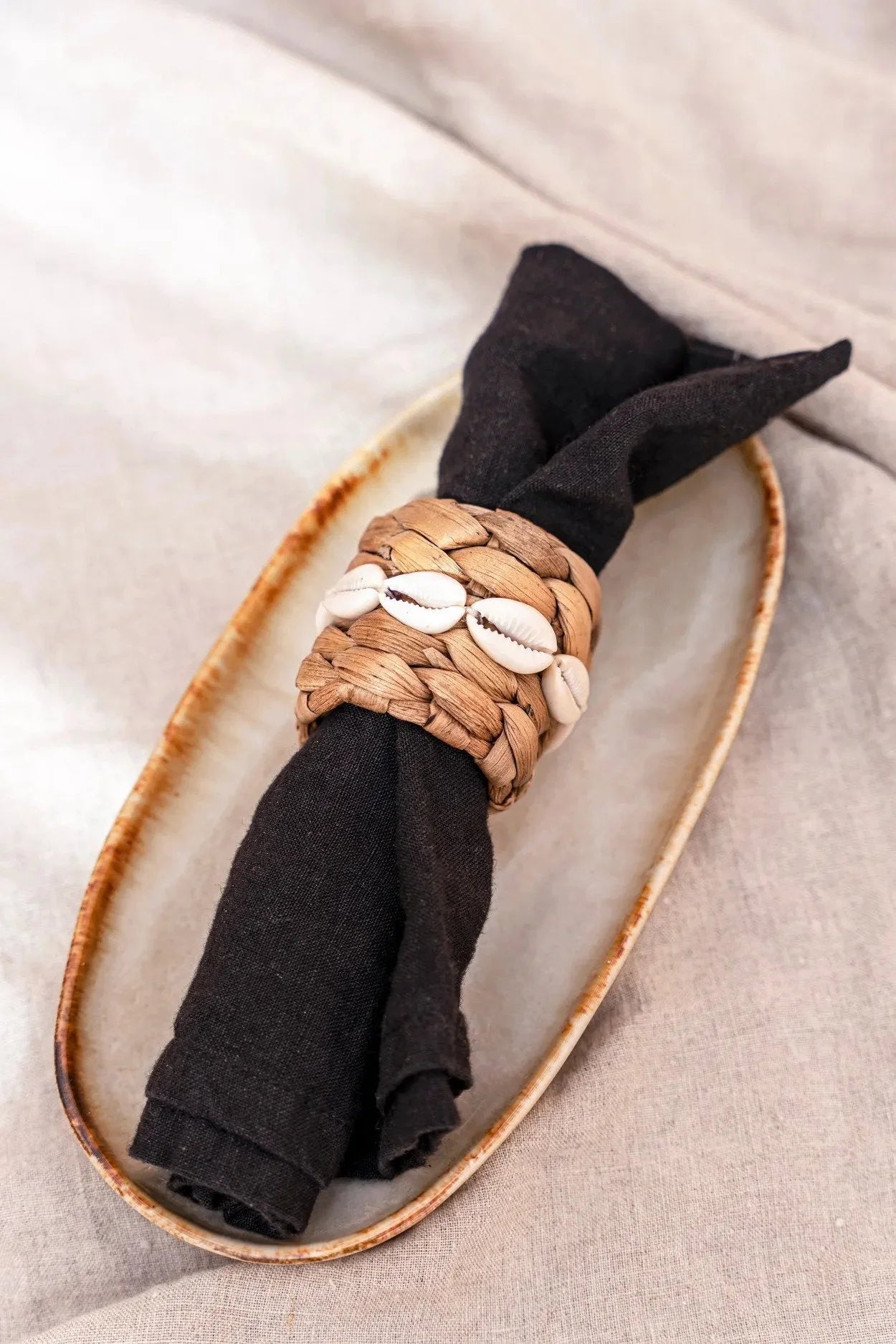 Assiette ovale en céramique blanche et brune avec napkin noir et anneau en coquillage