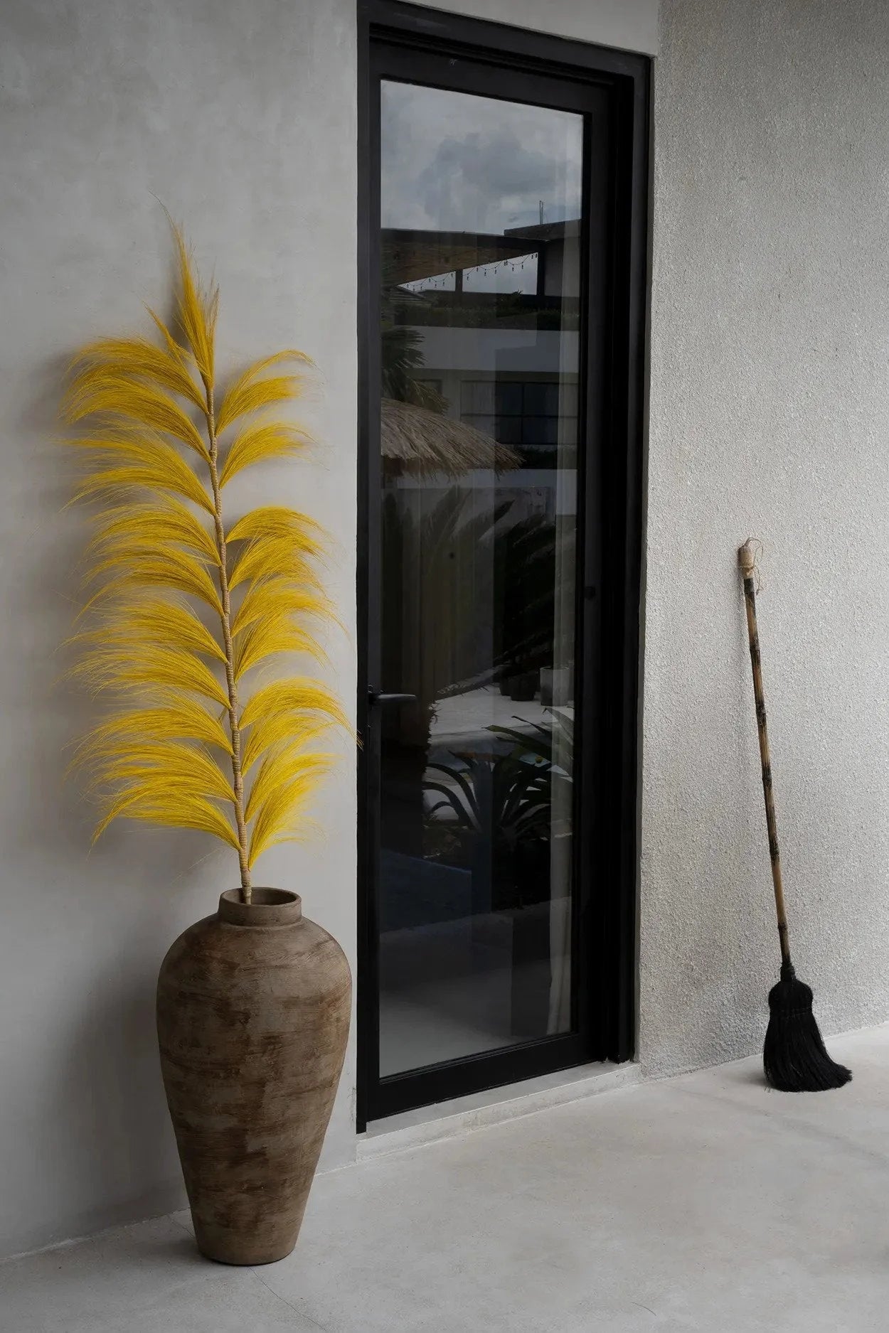 Vase rustique en fibres noires avec feuillage jaune, Balai décoratif en fibres