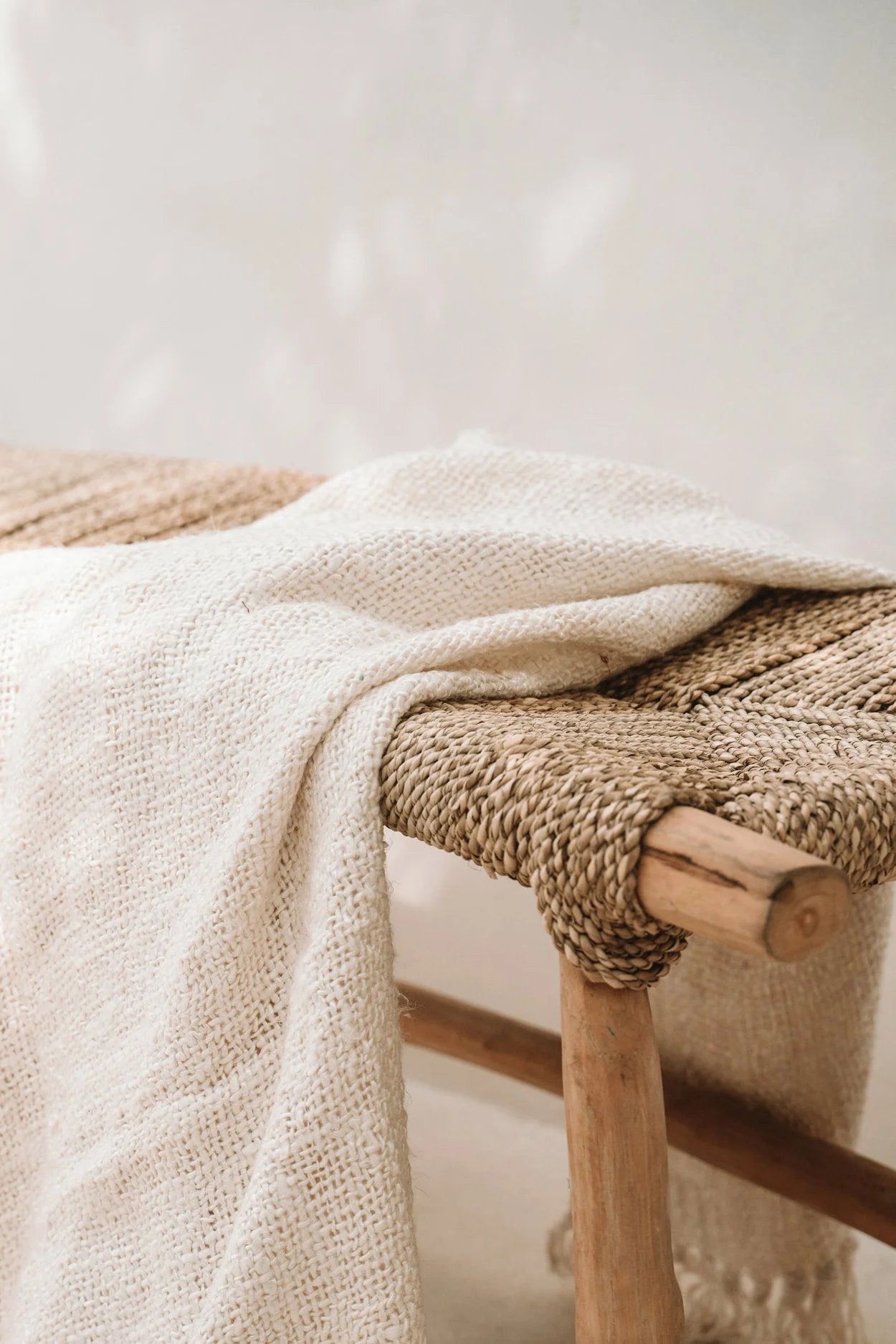 Plaid crème texturé sur banc en bois et fibre tressée pour intérieur ou terrasse