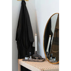 Tablier noir suspendu à un crochet doré sur banc en bois naturel 80x35 cm