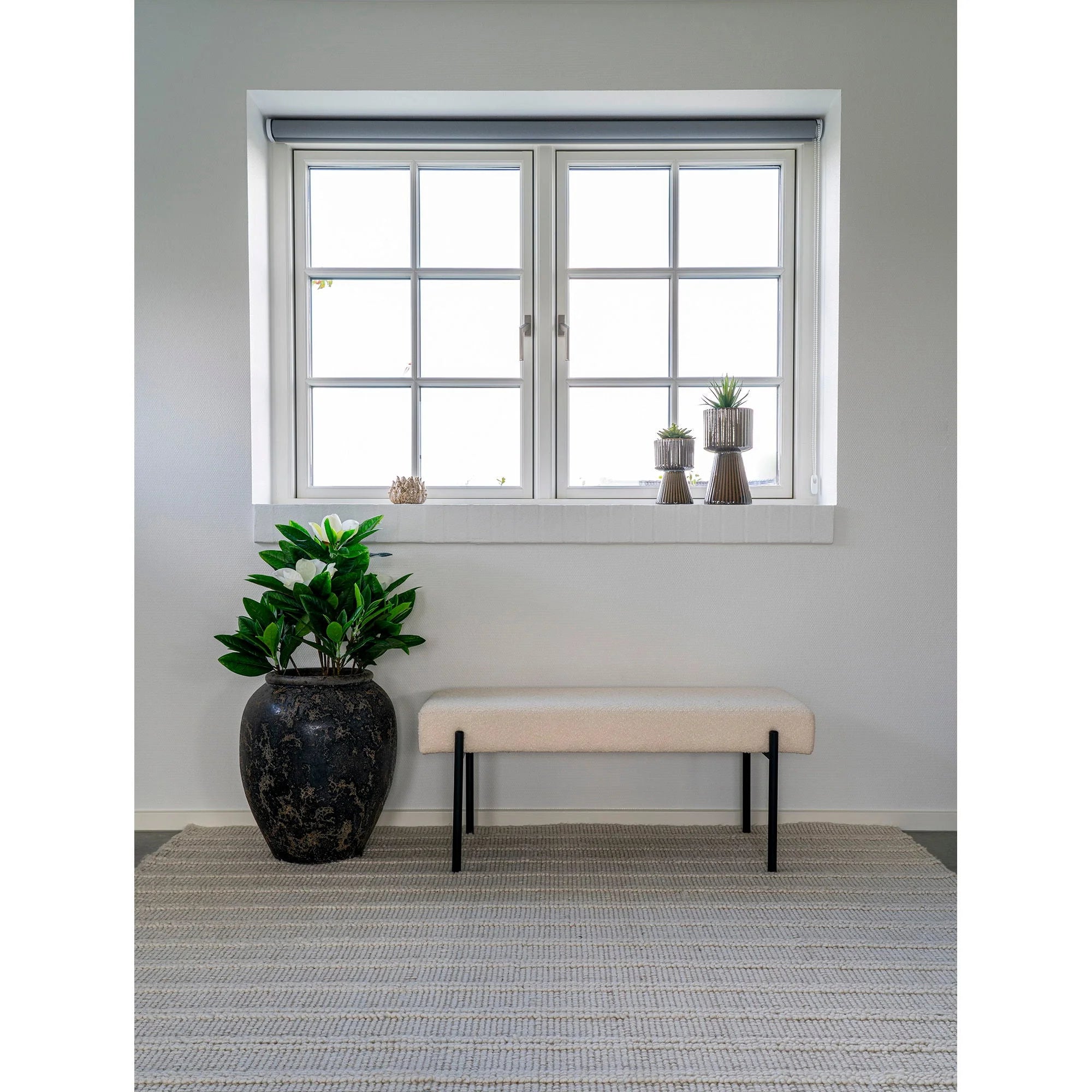 Fenêtre lumineuse avec banc en tissu bouclé beige et plante en pot
