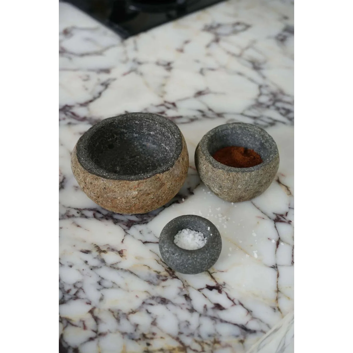 Mortier et pilon en pierre de lave grise granité avec épices rouges