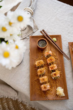 Sushi rolls avec toppings croustillants sur un plateau en bois de teck naturel