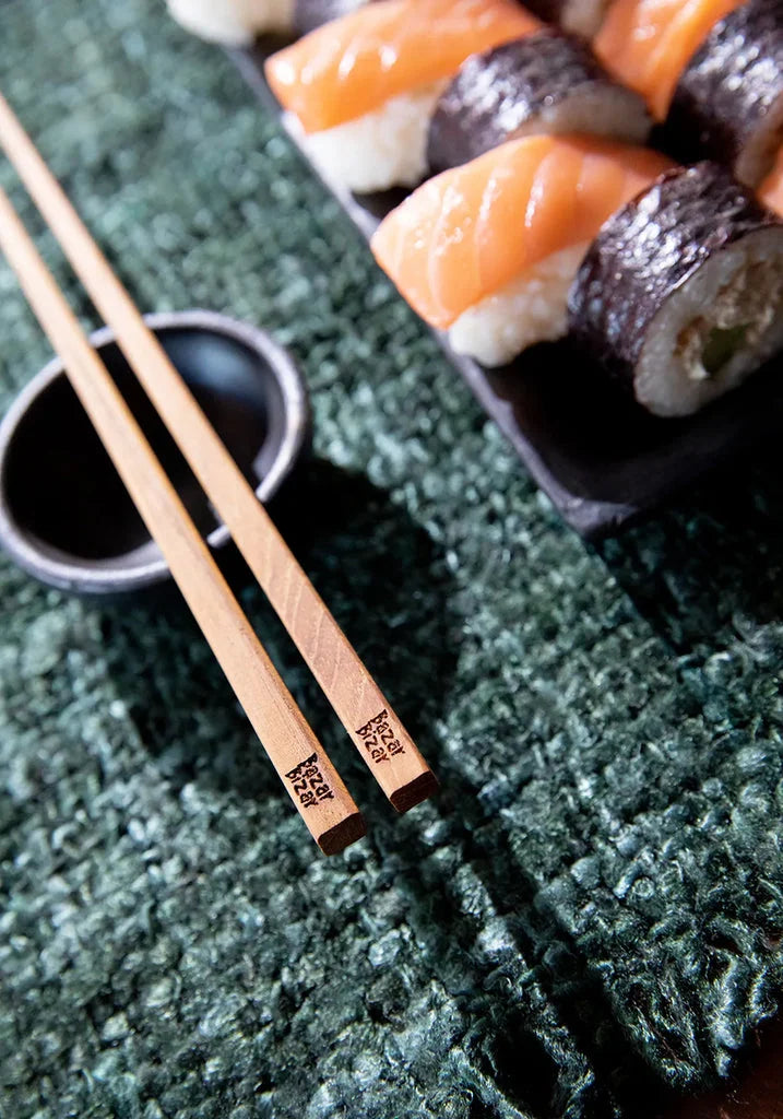 Sushi avec baguettes présenté dans Le Bol Brûlé Noir XS