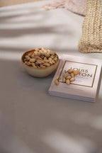 Bol en bois crème fait main rempli de pistaches à côté d’un livre