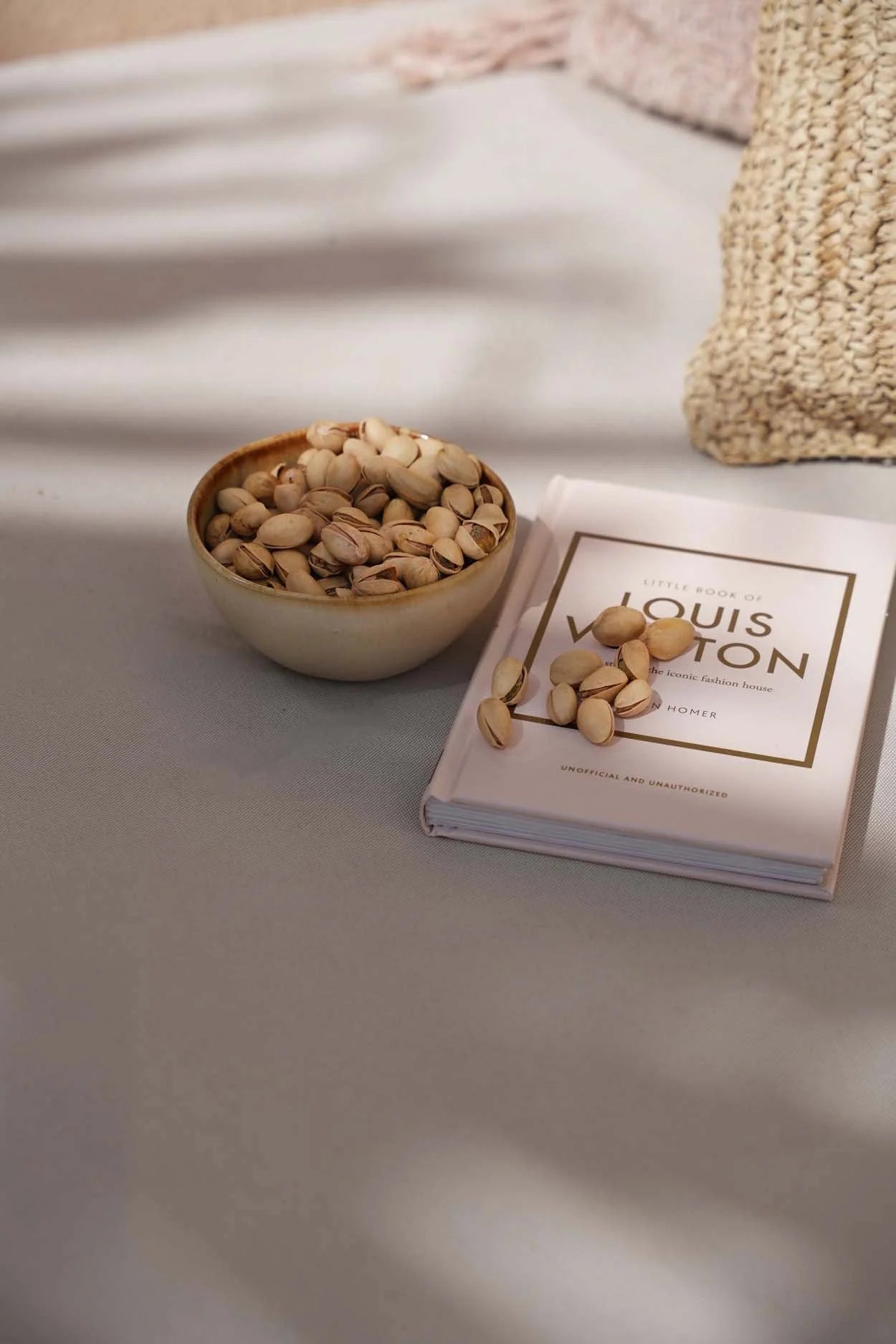 Bol en bois crème fait main rempli de pistaches à côté d’un livre