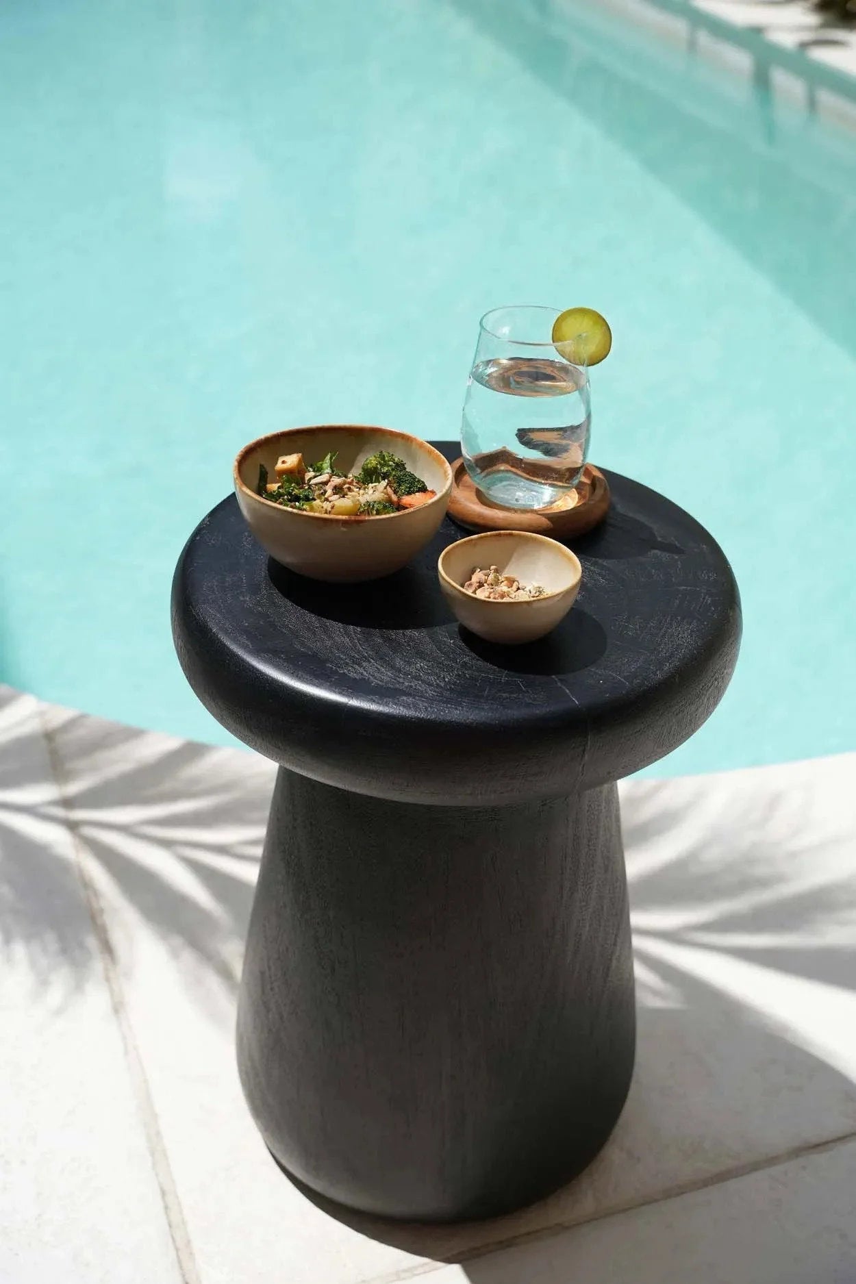 Table basse en pierre texturée noire, dessus rond et base effilée