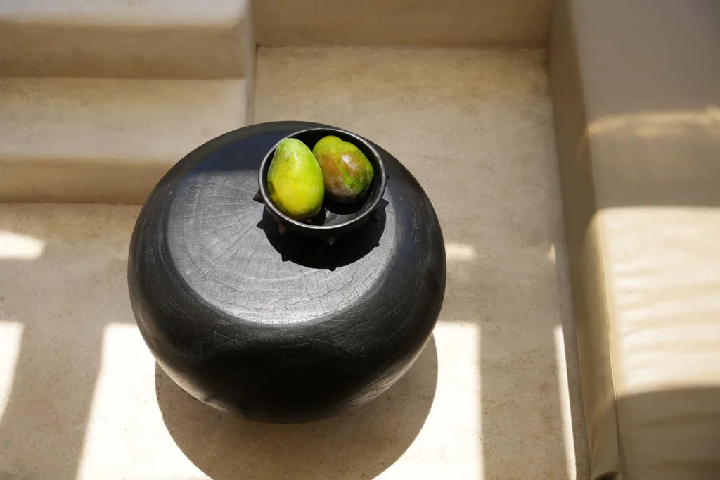 Pot rond noir avec des fruits pour le produit Le bol ethnique brûlé