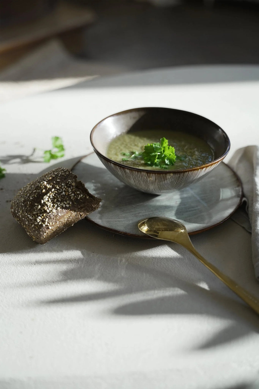 Bol en grès artisanal brun beige mat strié rempli de soupe verte au persil frais