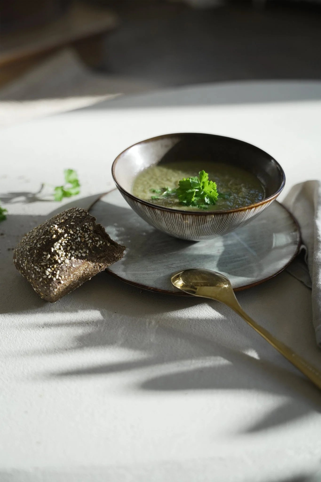 Bol en grès artisanal brun beige mat strié rempli de soupe verte au persil frais