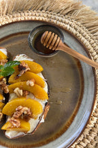 Assiette en grès émaillé dégradé ambré avec pêches, noix et menthe sur pain grillé