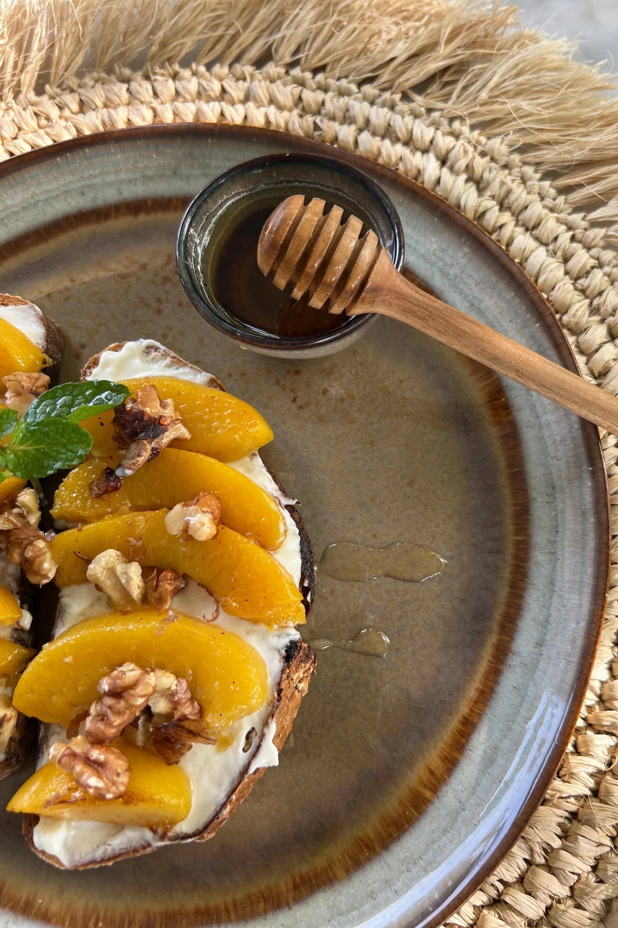 Assiette en grès émaillé dégradé ambré avec pêches, noix et menthe sur pain grillé