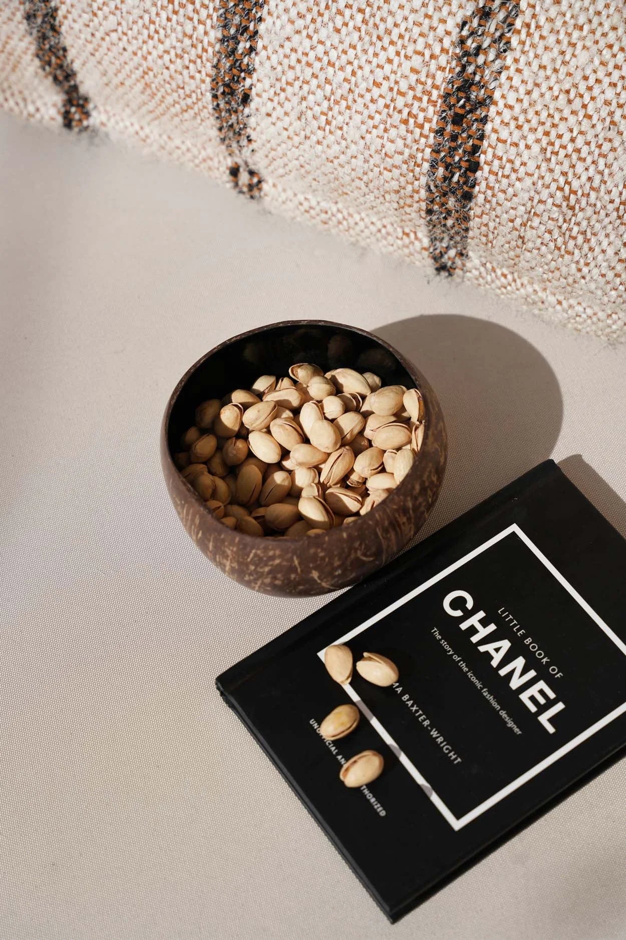 Bol en noix de coco naturelle brun foncé forme ronde rempli de pistachios