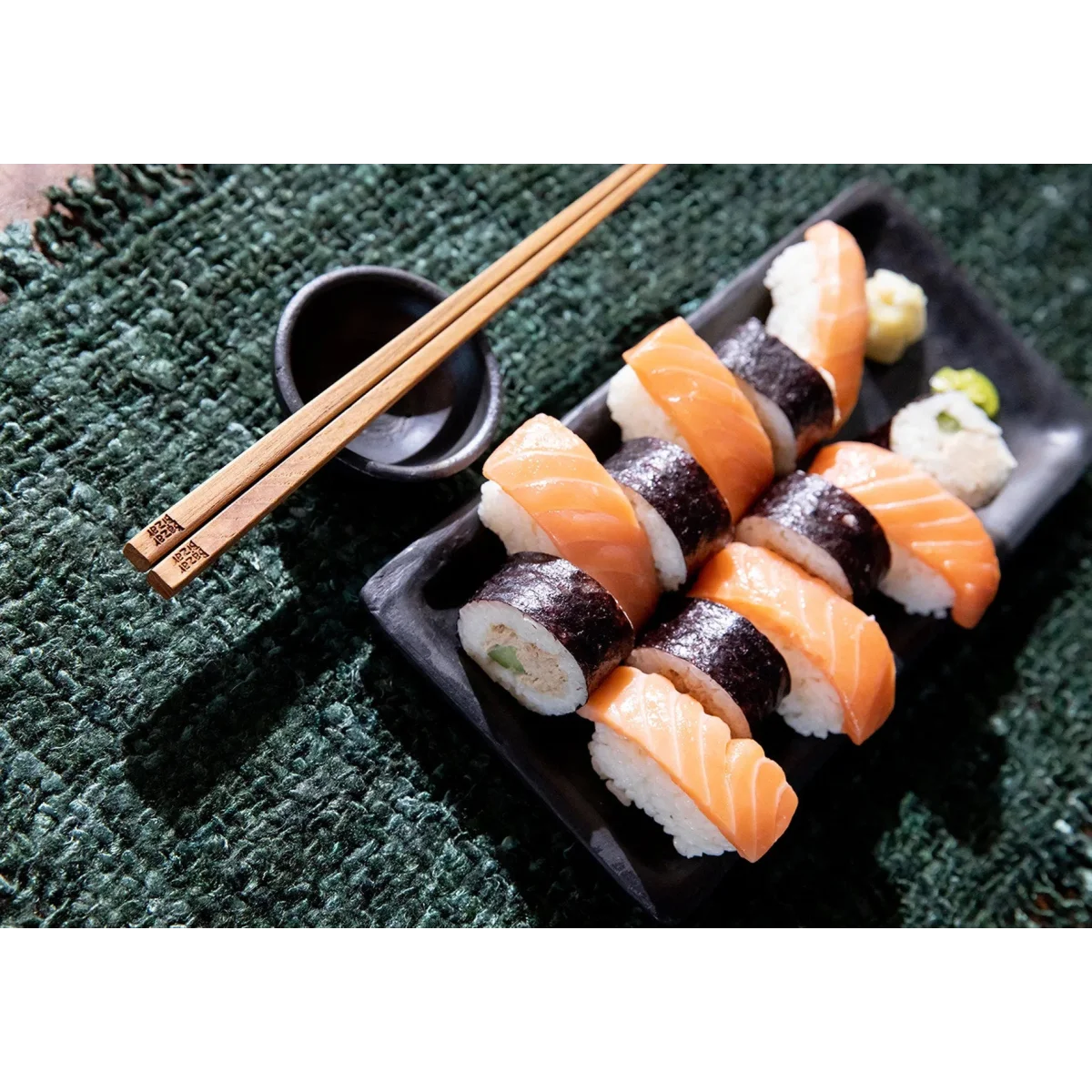 Plat de sushi frais avec salmon nigiri, maki, sauce soja et baguettes en terre cuite brûlée