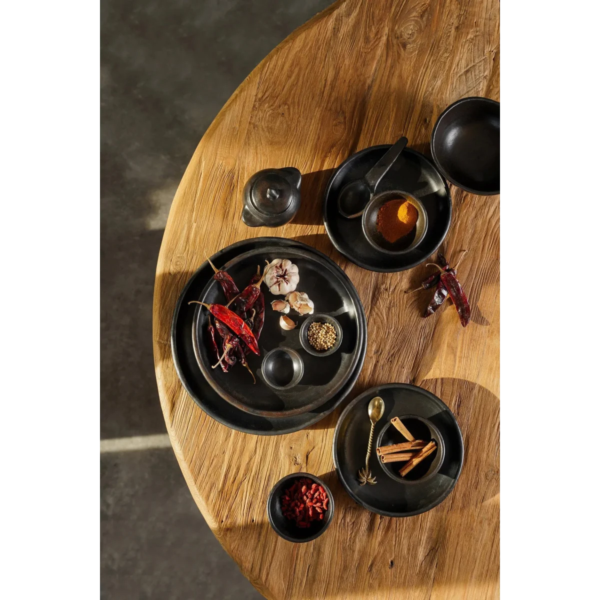 Collection de plats et bols en céramique noire brûlée remplis d’épices