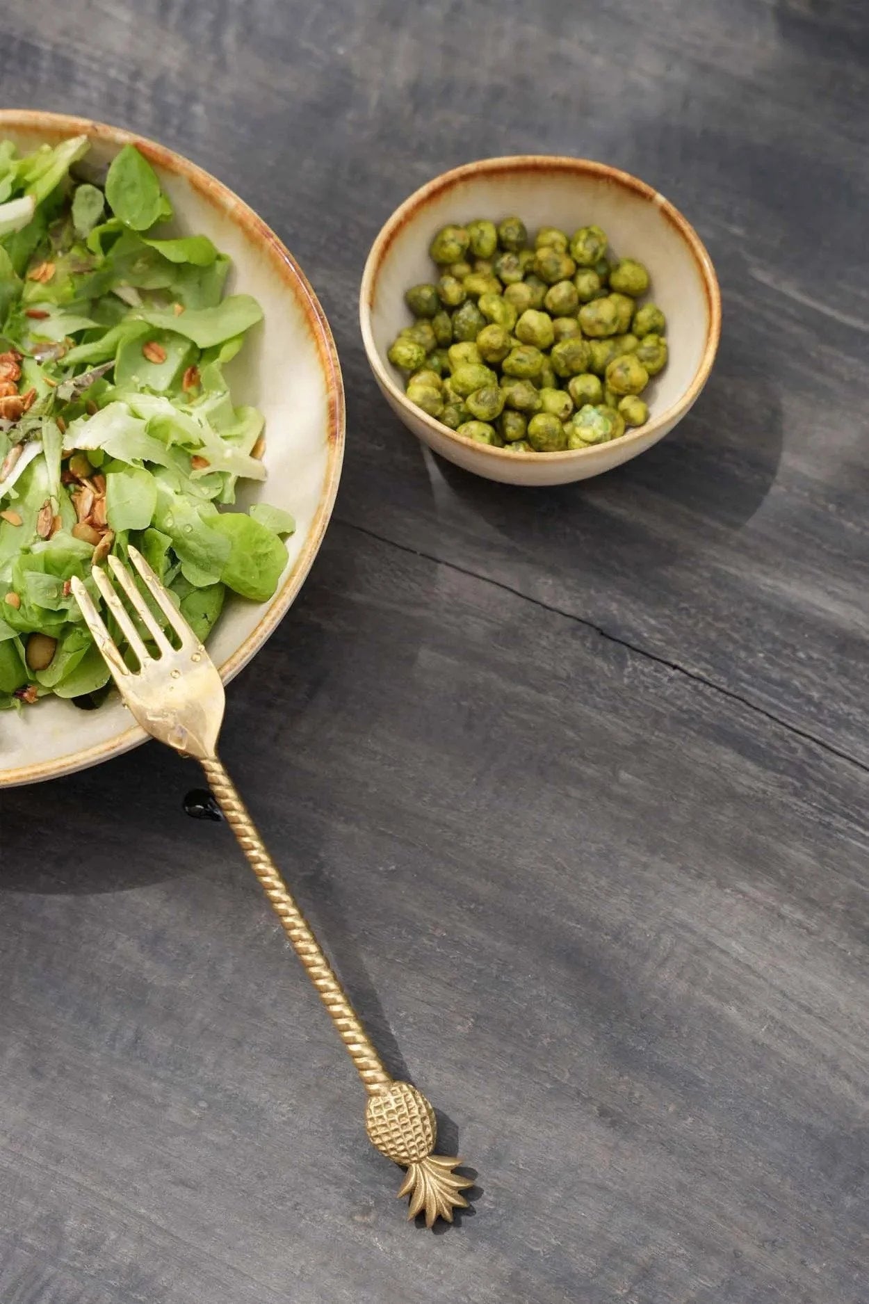 Salade avec pois verts et ananas dans une fourchette sur set de bols en céramique beige dégradé