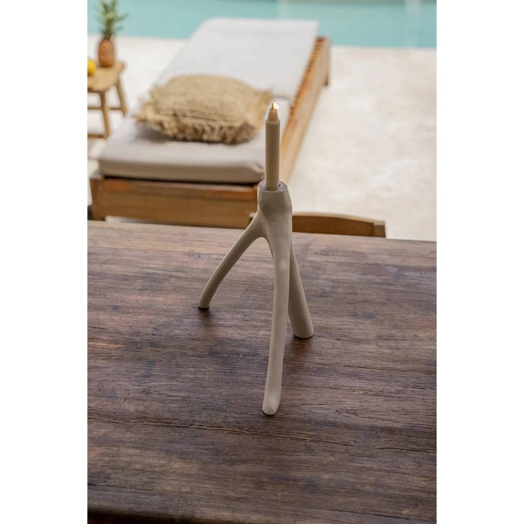 Bougeoir blanc en forme de branche organique avec bougie allumée sur une surface