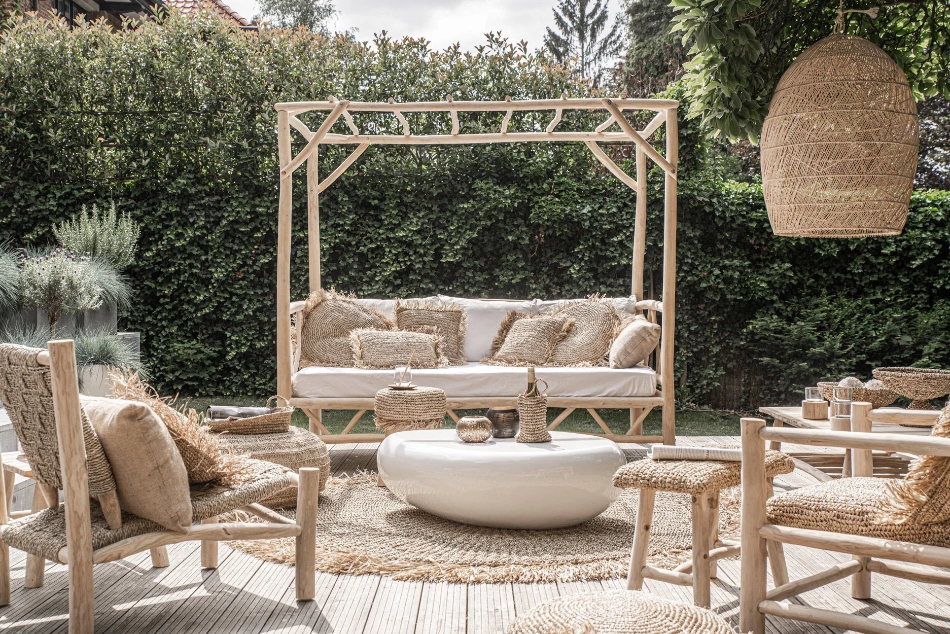 Lampe pendentif en osier beige tissé suspendue à une pergola en bois