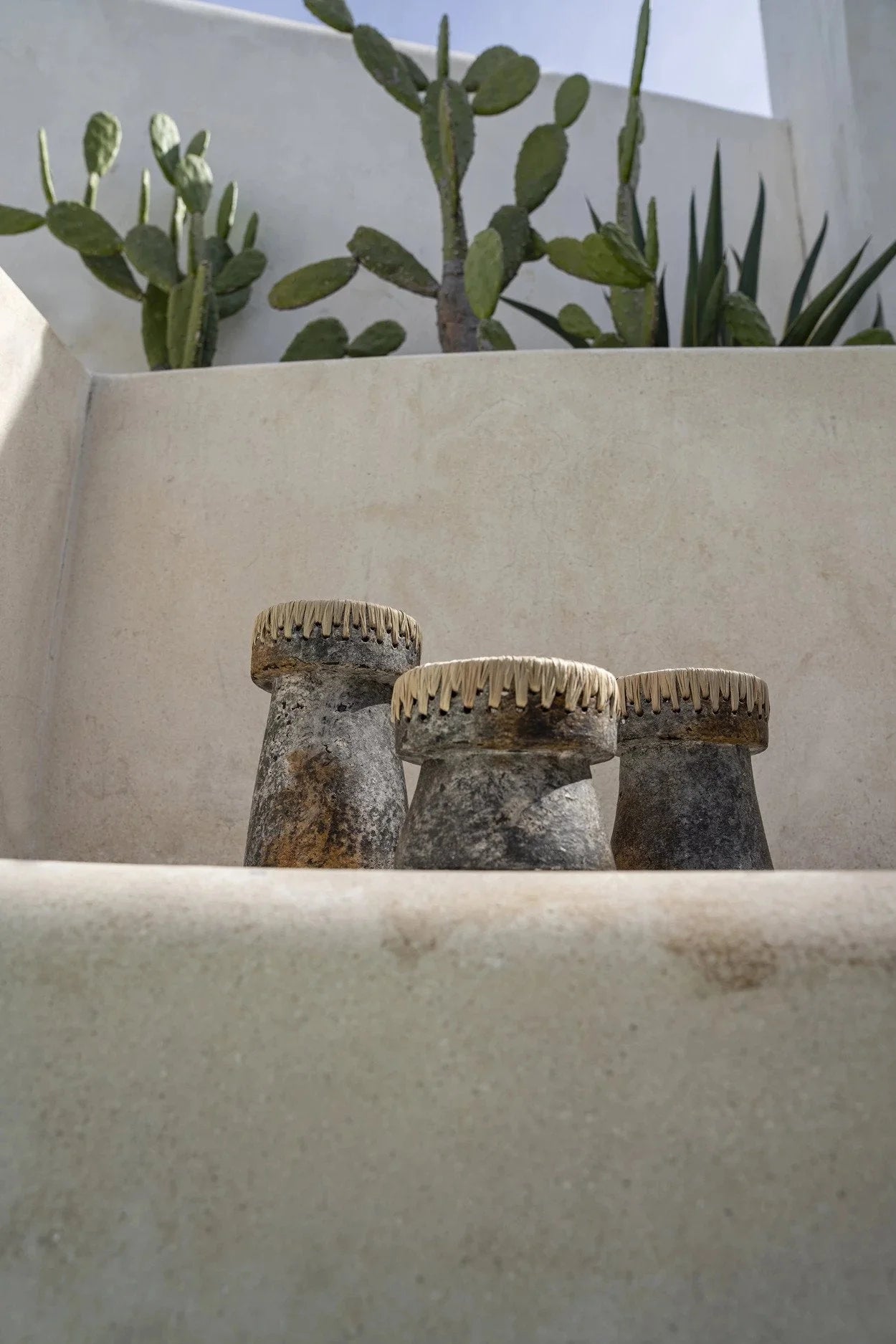 Trois bougeoirs en terre cuite gris marbré avec bordure en raphia tressé