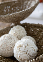 Sphères décoratives en coquillage dans des paniers tressés.