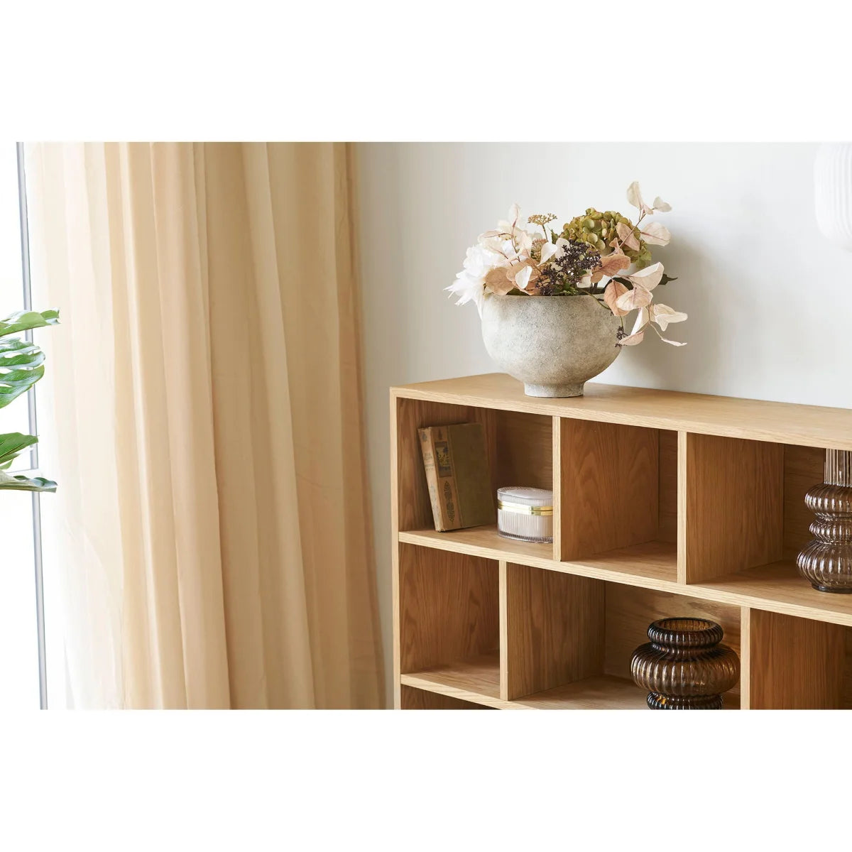 Étagère modulaire en bois clair avec décorations, idéale avec cache-pot en céramique gris