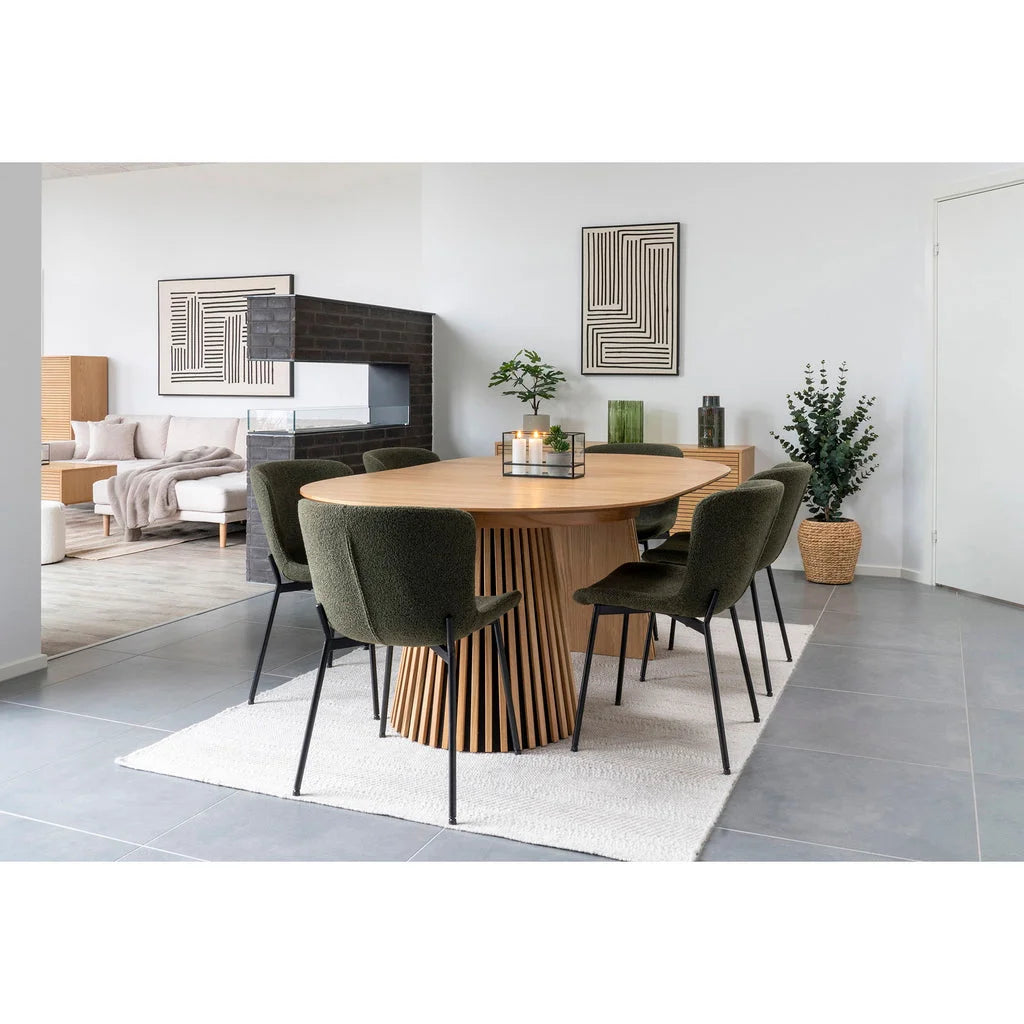 Table à manger ovale en bois clair avec base cylindrique à lattes, entourée de six chaises vert foncé